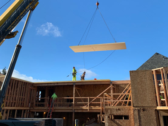 A spruce cross-laminated timber panel moves into place