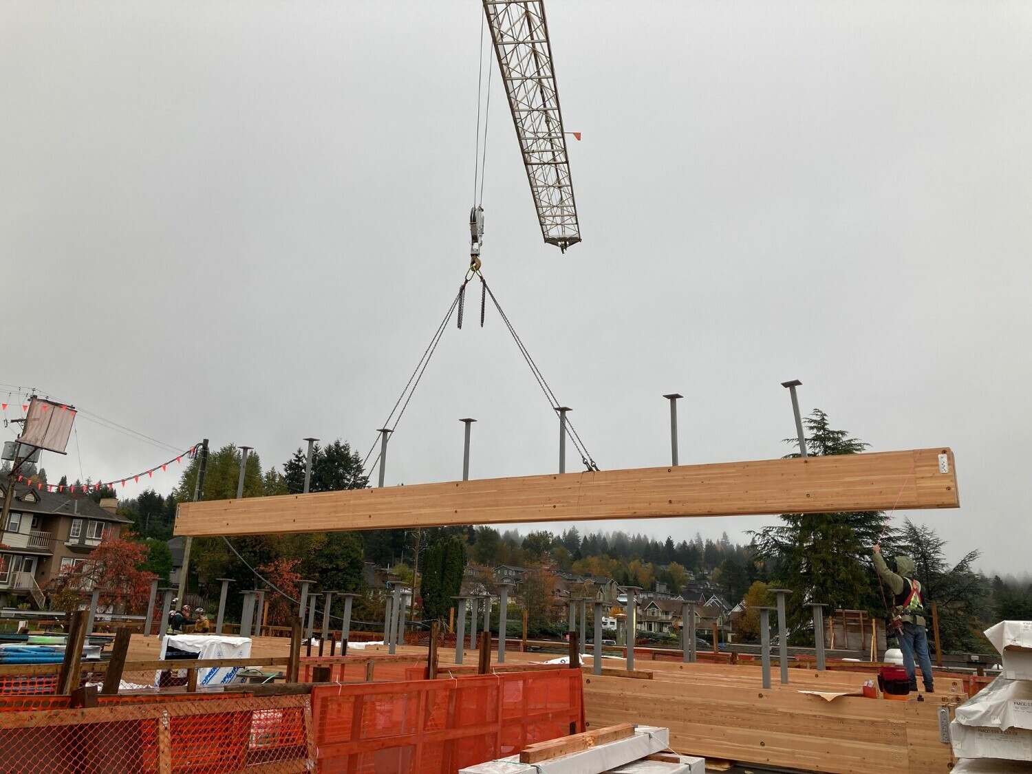 An exposed Glulam beam moves into place via a crane